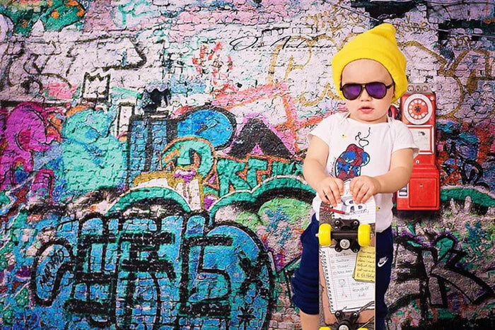 Kleiner Junge steht vor einer Graffitiwand