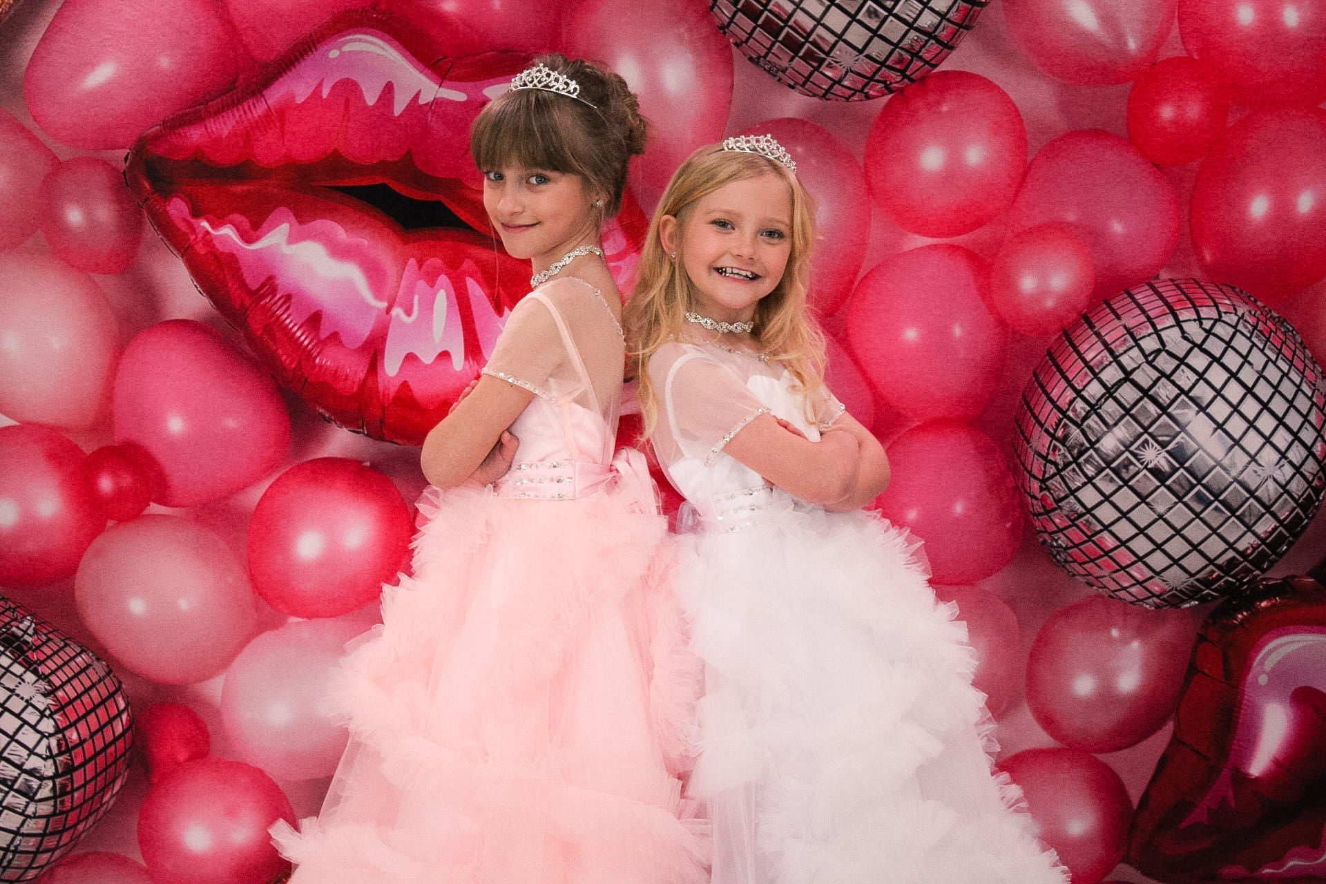 Zwei Mädchen stehen vor einer roten Ballonwand