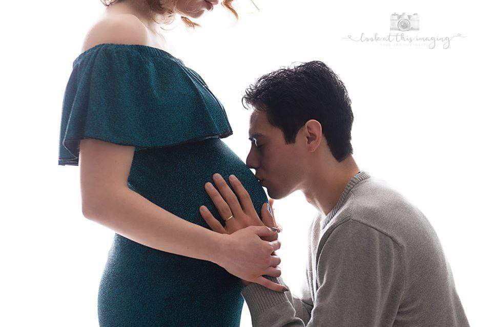 Ein werdender Vater küsst den schwangeren Bauch der werdenden Mutter