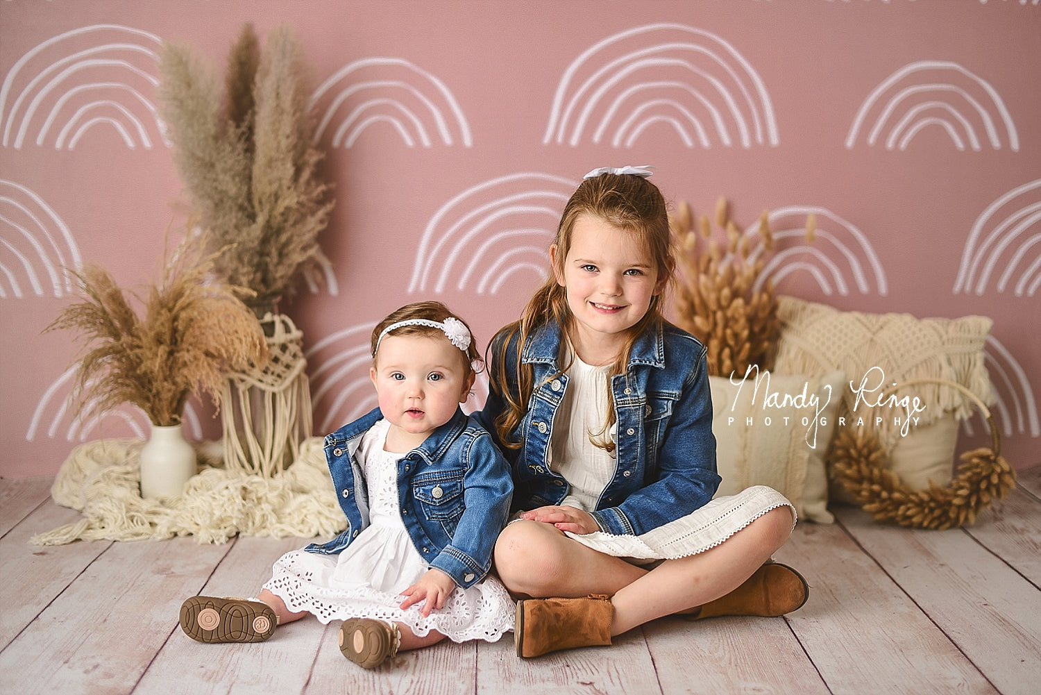 Zwei Mädchen sitzen vor einer rosa Wand im Boho-Stil