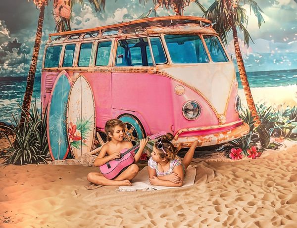 Bruder und Schwester sitzen vor einem rosa Auto am Strand